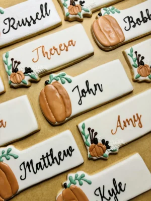 Thanksgiving themed place card cookies with pumpkins, fall florals, and guests' names