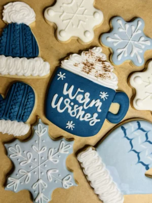 Winter themed cookies with snowflakes, gloves, hats, and a cup of hot chocolate with the words "warm wishes"