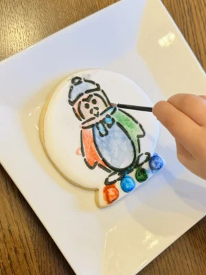 A child painting a penguin paint your own cookie.