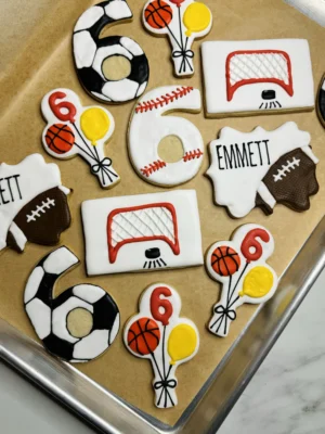 Sports themed 6th birthday cookies with soccer balls, footballs, baseballs, basketballs, and ice hockey nets.